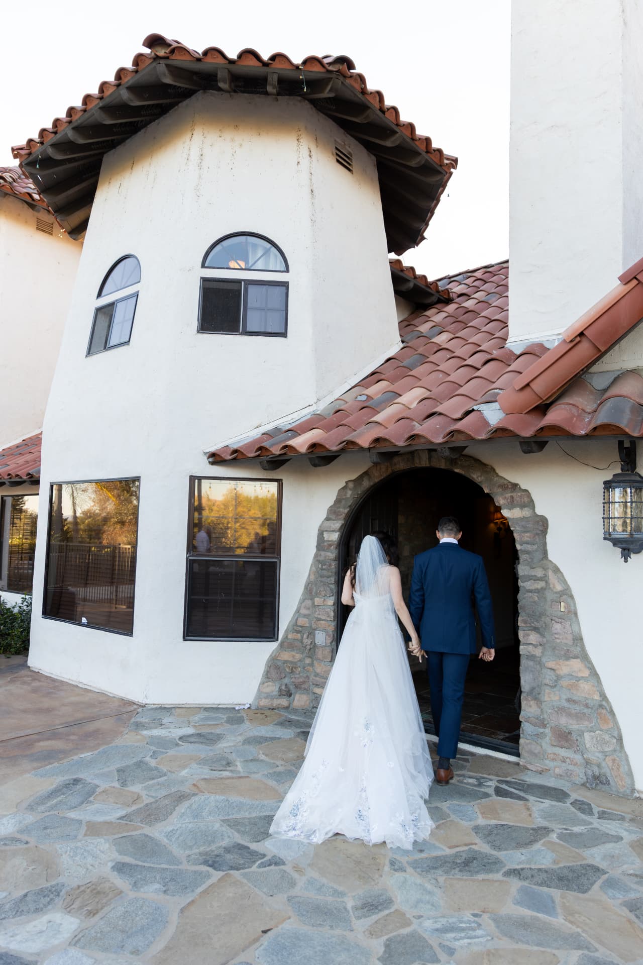 Katherine and Colin walking together into a Spanish-style winery after their ceremony