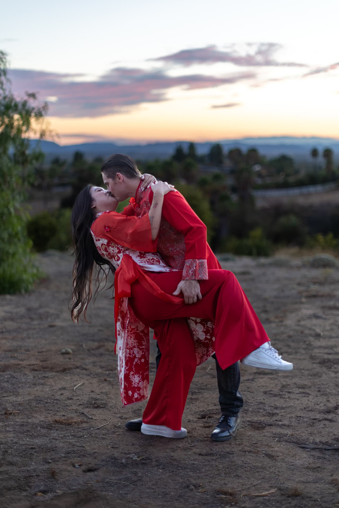 Man dipping a woman for a kiss in a rocky field against a vibrant sunset sky, Thanh & Nicholas engagement