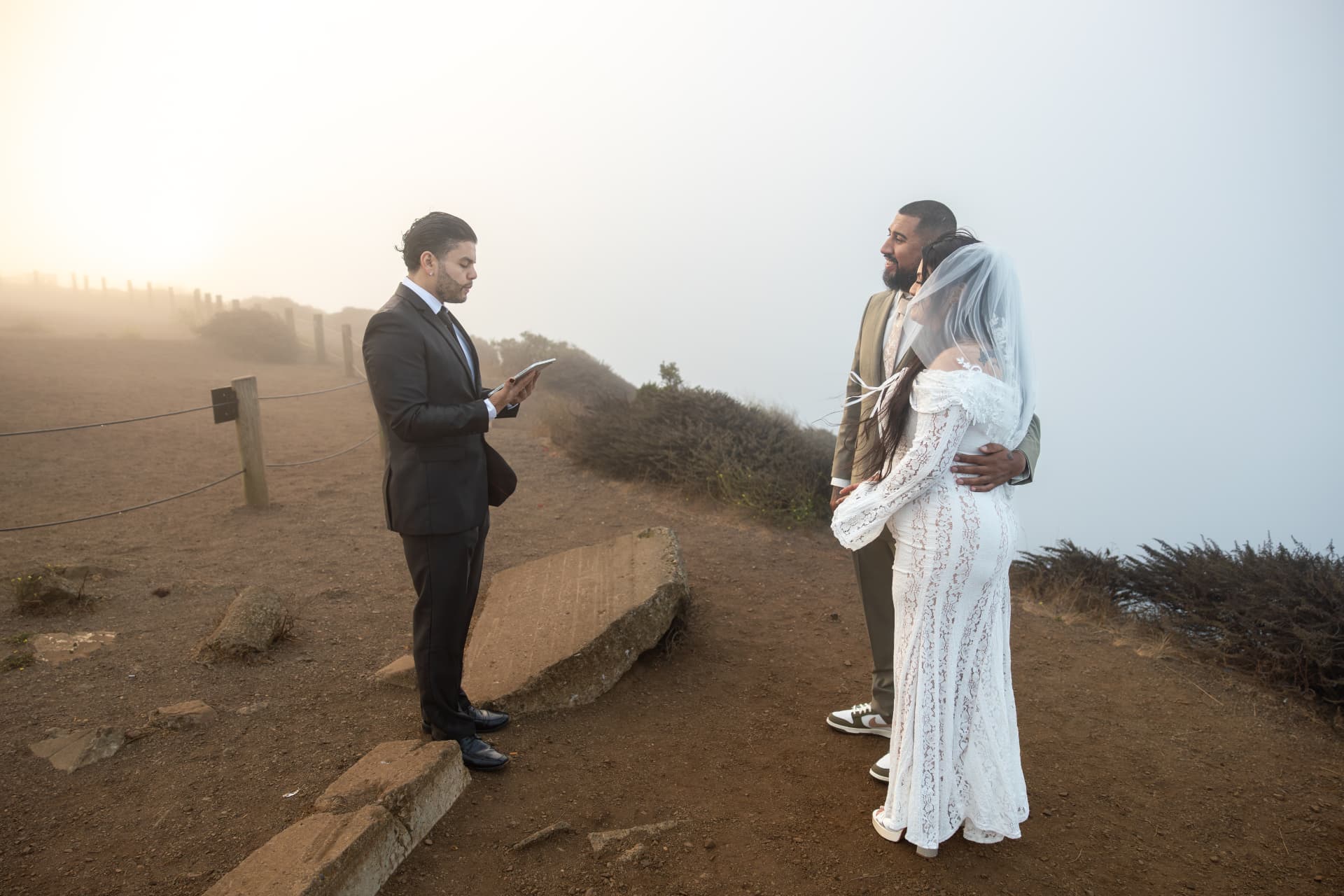 Bride and groom smiling at each other during their outdoor ceremony as the officiant reads from a tablet, Crystal & Joey wedding
