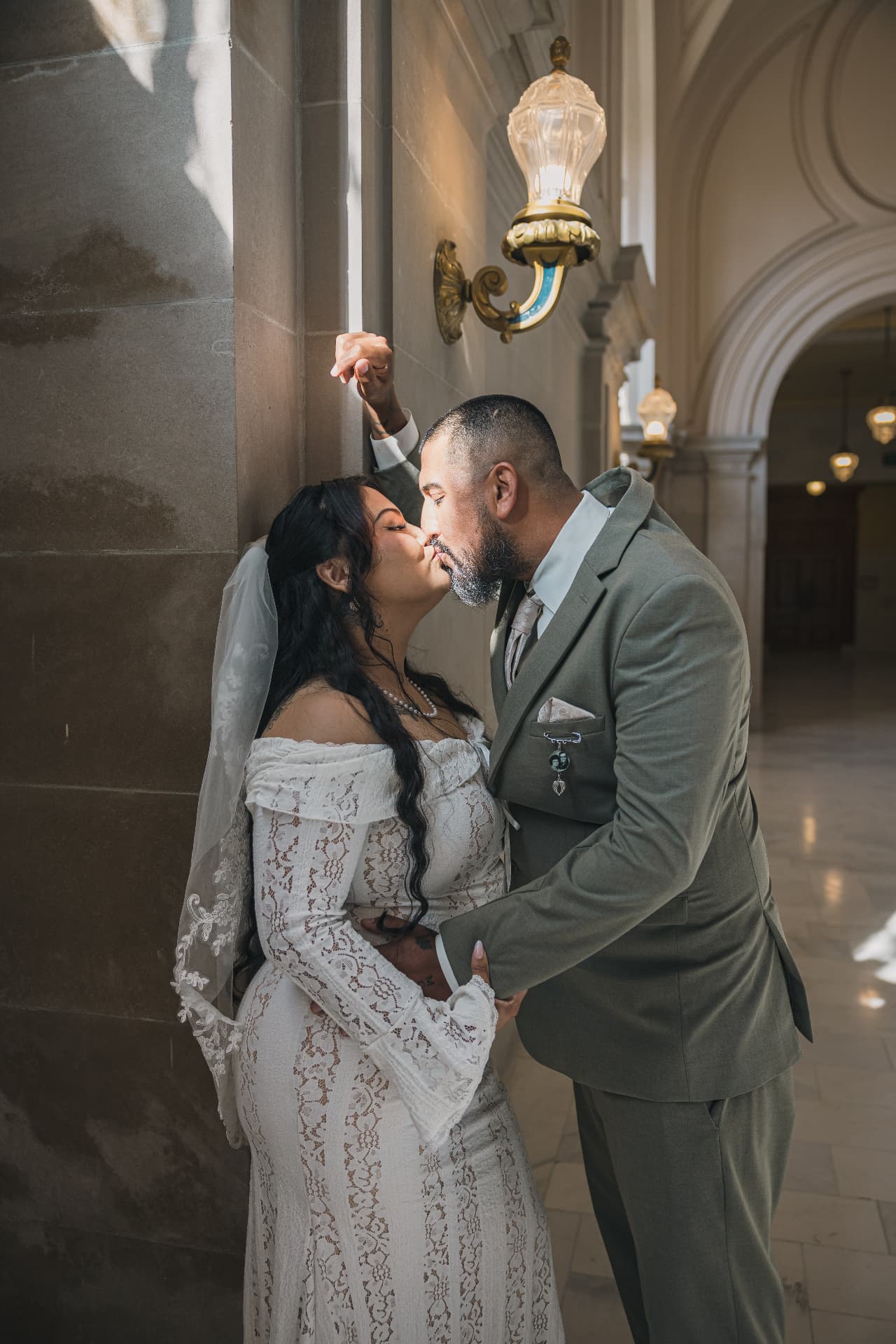 Bride and groom kissing in a dramatically lit stone corridor