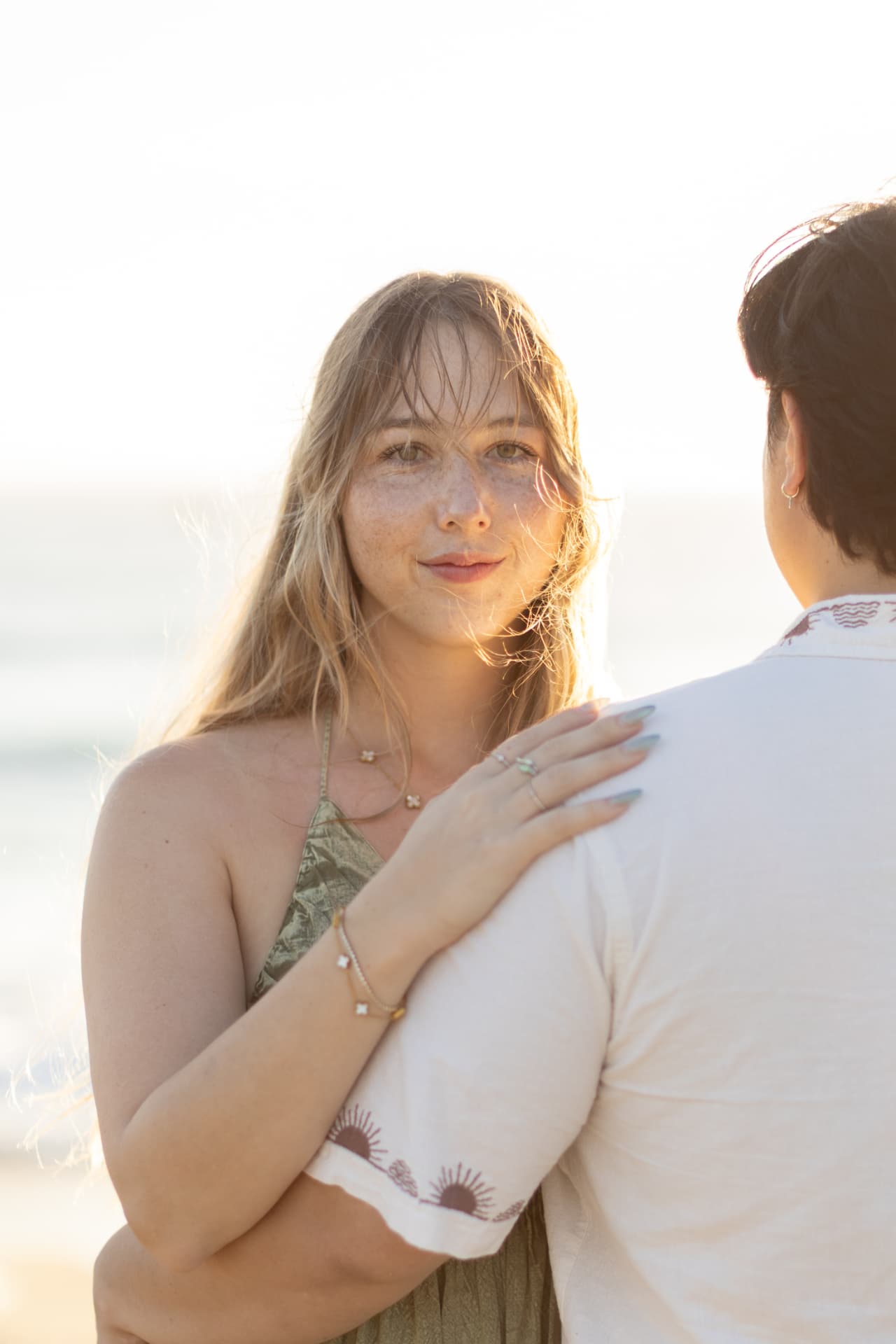 Close-up of a smiling woman with freckles in backlight, her hand on her partner's shoulder, Anna & Brian couples session