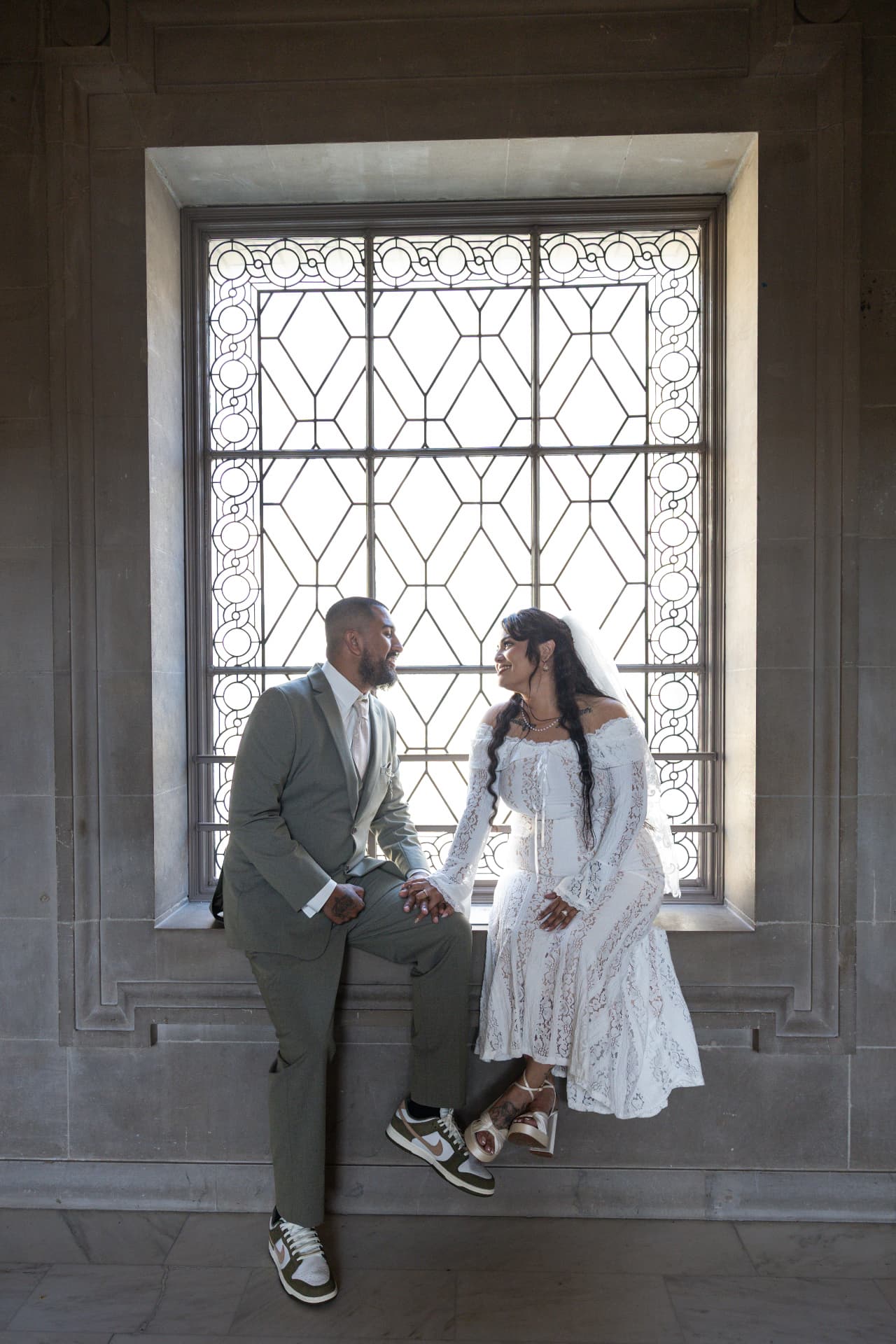 Newlyweds sitting together in front of a large geometric stained-glass window