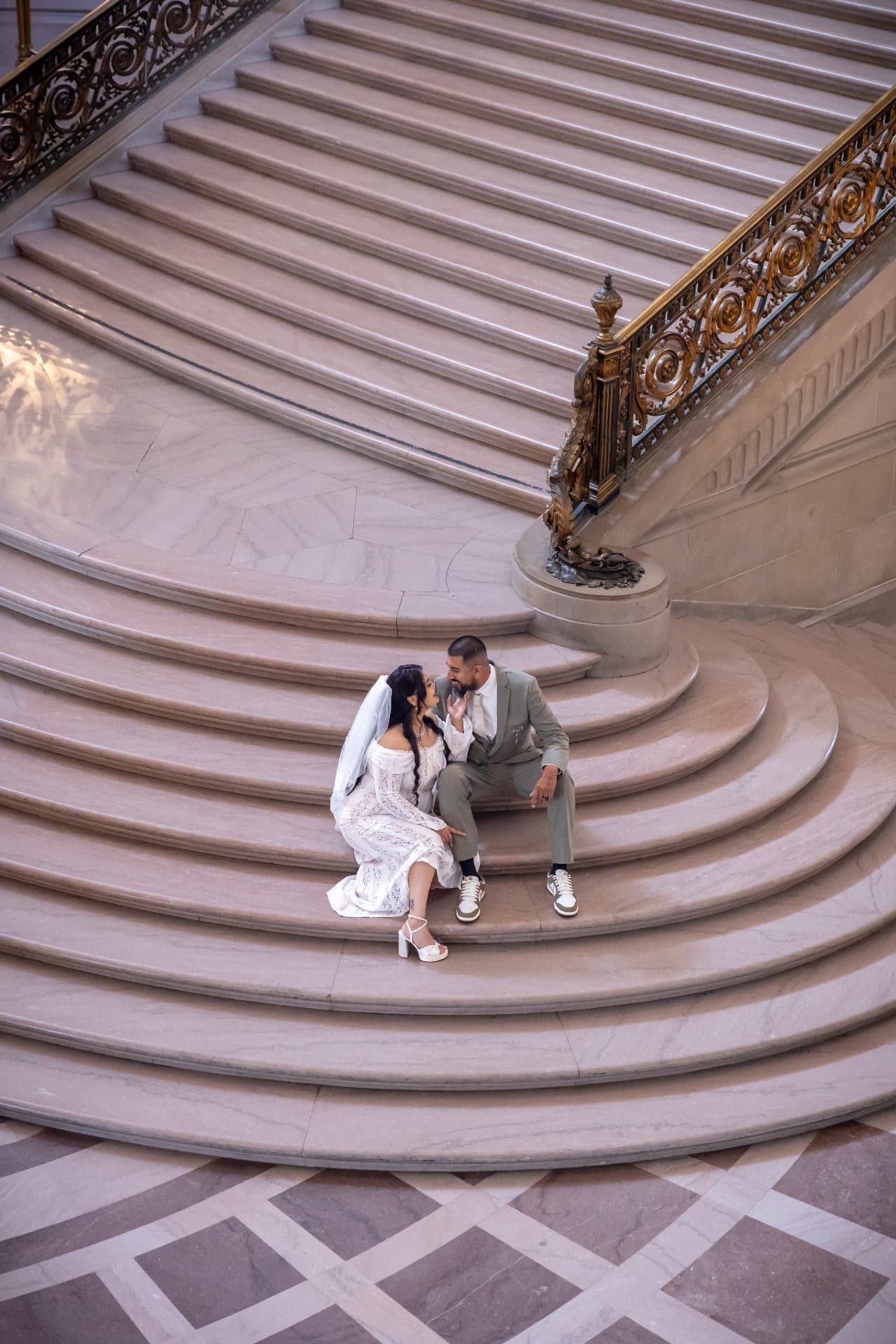 Newlyweds seated together on curved ornate stairs