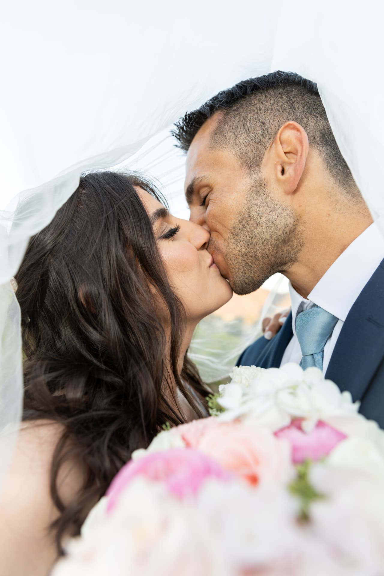 Close portrait of Katherine and Colin kissing beneath her veil