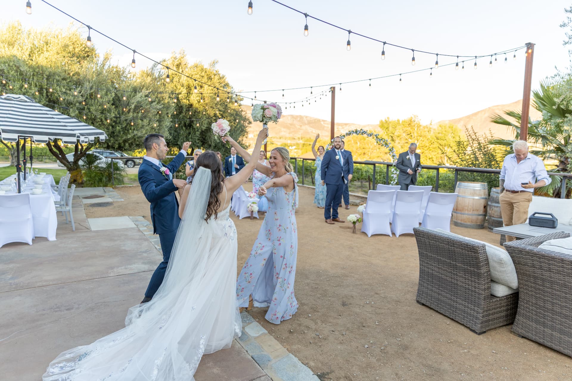 Katherine celebrating with Colin and her guests beneath string lights after the ceremony