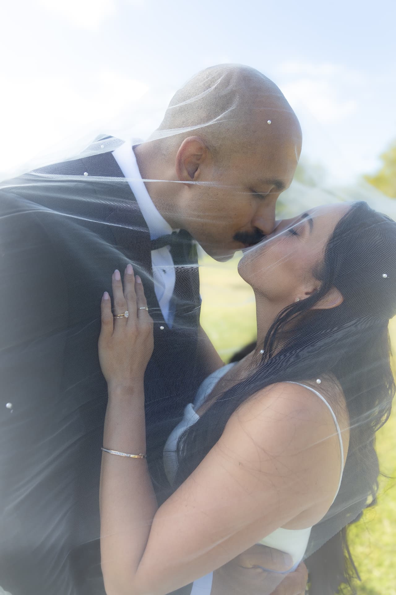 Bride and groom kissing beneath a soft translucent veil